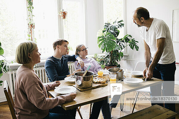 Family talking with dad standing near table at home