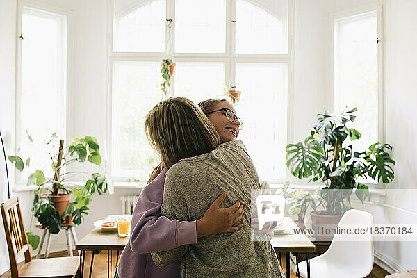 Eltern  die ihre Tochter umarmen  während sie zu Hause stehen