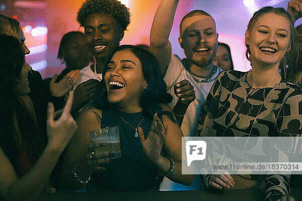 Fröhliche weibliche und männliche Freunde tanzen beim Feiern einer Wochenendparty in einem Club