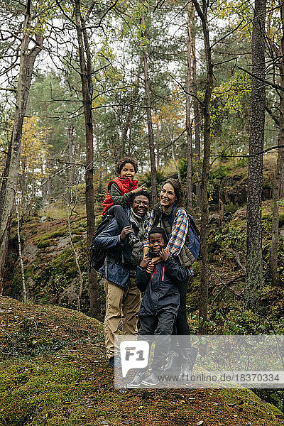 Glückliche Familie  die in den Ferien miteinander im Wald steht