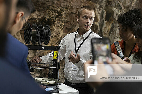Geschäftsmann erklärt Kollegen den 3D-Drucker während eines Seminars im Kongresszentrum