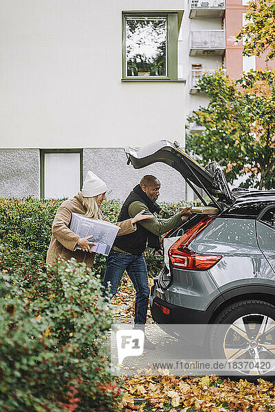Reife Frau hilft Mann beim Beladen des Kofferraums während des Umzugs eines Hauses