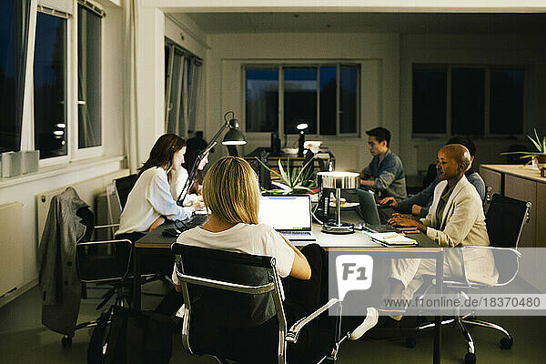 Business colleagues working late while sitting at desk in office
