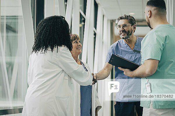 Männlicher Arzt beim Händeschütteln mit einer Kollegin im Krankenhaus