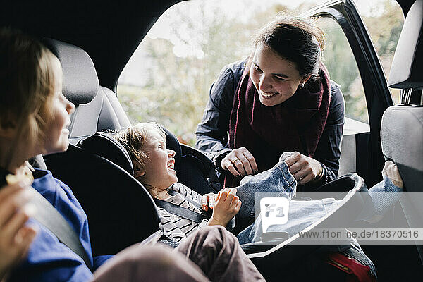 Glückliche Mutter kitzelt Tochter im Auto sitzend