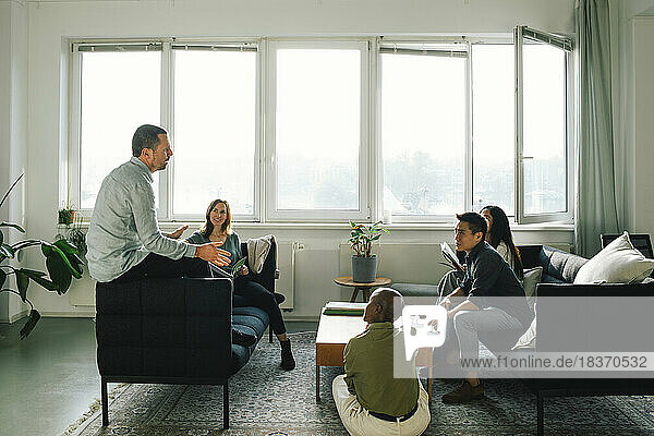 Multirassische Geschäftsleute  die in einer Sitzung im Büro miteinander diskutieren