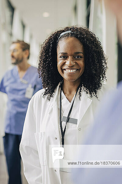 Porträt einer lächelnden Ärztin mit lockigem Haar im Krankenhaus