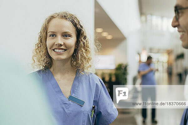 Lächelndes weibliches Gesundheitspersonal mit Kollegen im Krankenhaus