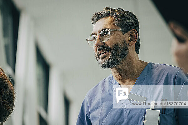 Low angle view of smiling mature male doctor wearing eyeglasses at hospital