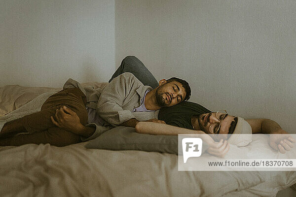 Man relaxing with boyfriend while lying on bed at home