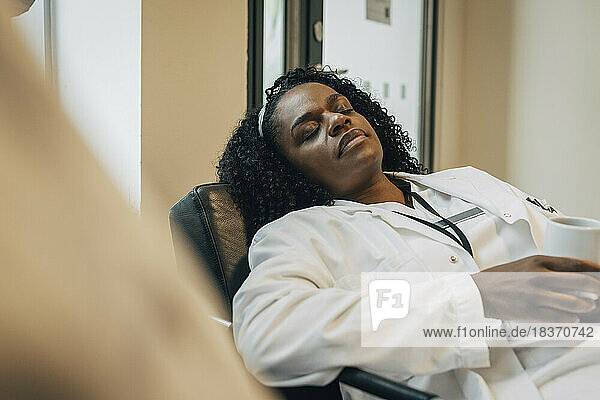 Müde Ärztin beim Nickerchen während der Kaffeepause im Krankenhaus