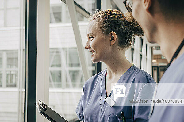 Lächelnde Krankenschwester schaut durch ein Fenster im Krankenhaus