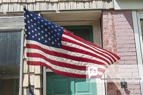American flag in front of a building,  a shop window on main street.