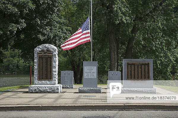 War memorials  inscribed headstones and American flag honoring US war veterans in a graveyard.