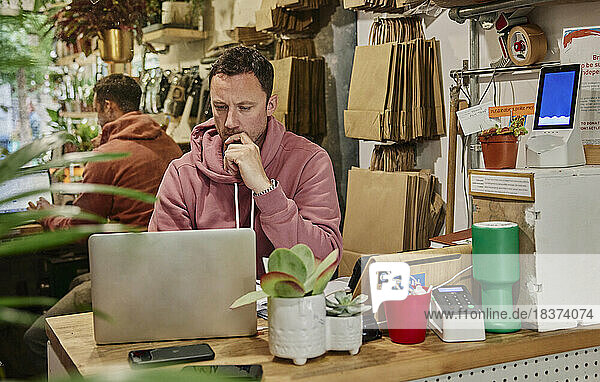 Man using laptop on shop counter