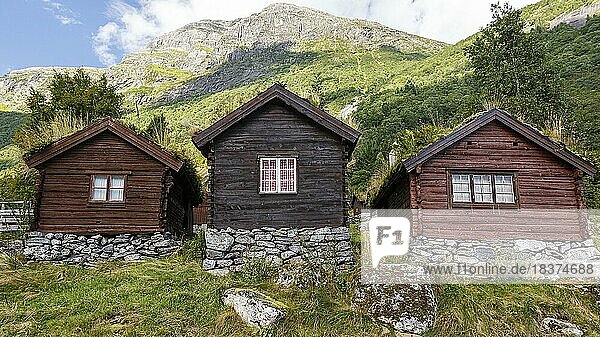 Drei Holzhütten stehen an einem Berg in Norwegen