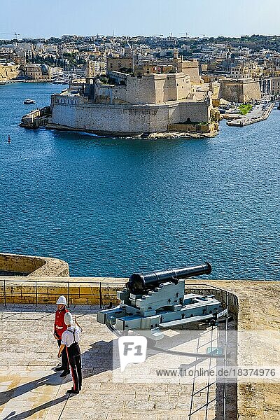 Blick über ehemaliger Exerzierplatz neben Upper Barraka Gardens in La Valletta mit Salut Kanone daneben zwei Soldaten in historische Uniform auf historisches Fort St. Angelo auf Halbinsel Birgu  La Vittoriosa  Malta  Europa