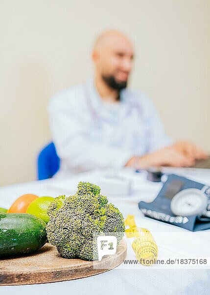 Fokus auf Gemüse von Ernährungswissenschaftler mit Laptop am Schreibtisch. Ernährungsberaterin arbeitet am Laptop  gibt Onlineberatung für Kunden in der Klinik  Fokus auf Gemüse