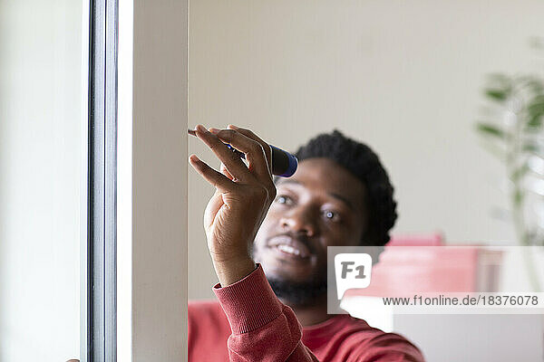 Young man repairing window with screwdriver at home