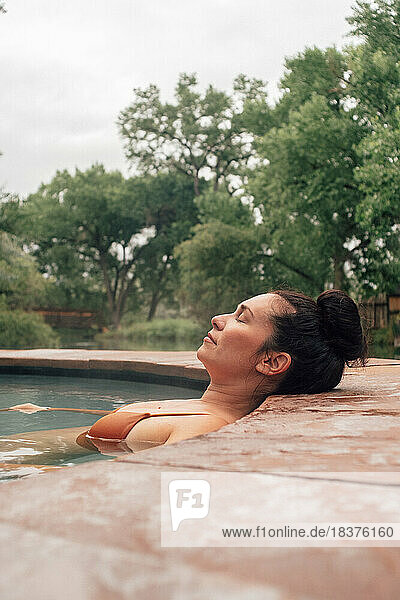Woman lying in swimming pool in spa resort
