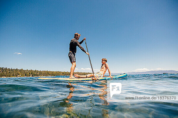 USA  California  Father and son (12-13) paddleboarding on Lake Tahoe
