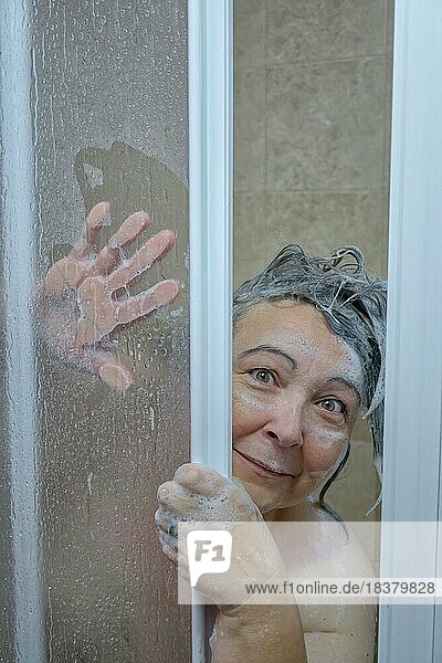 Frau in der Dusche mit Seife bedeckt schaut in die Kamera