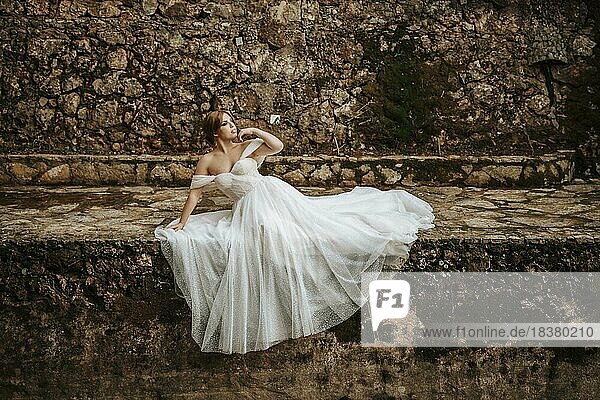 Verträumte Porträts einer schönen Braut am steinernen Flussufer