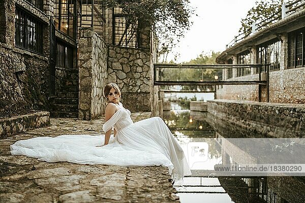 Verträumte Porträts einer schönen Braut am steinernen Flussufer
