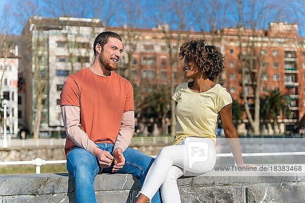Ein gemischtrassiges Paar auf der Straße in der Stadt  Lifestyle  sitzt lächelnd und spricht am Wochenende
