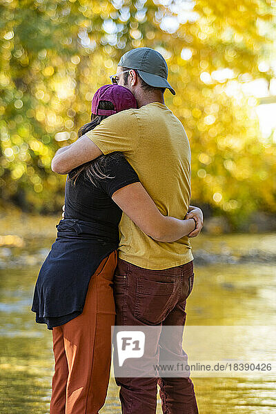 millennial couple embrace at river in fall near Sun Valley Idaho