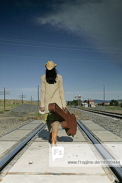 Santa Fe New Mexico United States Woman with guitar walking down railroad tracks Model released