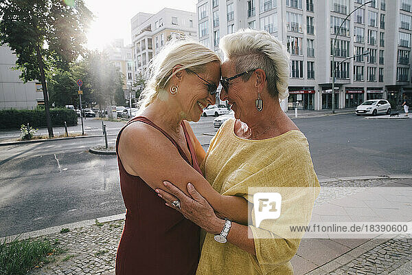 Zwei ältere Frauen umarmen sich auf der Straße in der Stadt
