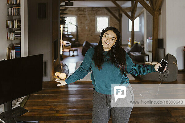 Frau tanzt im Wohnzimmer  während sie zu Hause Musik hört