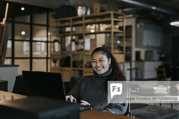 Porträt einer glücklichen Geschäftsfrau mit Laptop am Schreibtisch in einem kreativen Büro