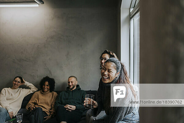 Fröhliche Geschäftsfrau  die mit ihren Kollegen Kaffee trinkt  während sie eine Pause in einem Start-up-Unternehmen macht