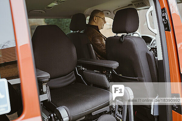Motorisierter Rollstuhl gegen Mann mit Behinderung  der in einem Lieferwagen sitzt