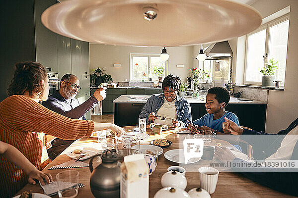 Eine Mehrgenerationen-Familie  die gemeinsam das Essen auf dem Esstisch zu Hause genießt
