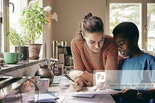 Mother assisting son while doing homework at home