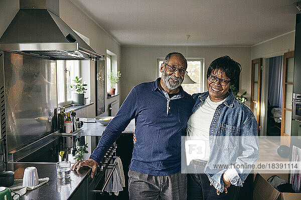 Porträt eines glücklichen älteren Paares  das zusammen in der Küche zu Hause steht