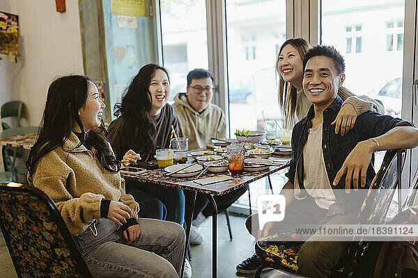 Happy male and female friends enjoying together during lunch at restaurant