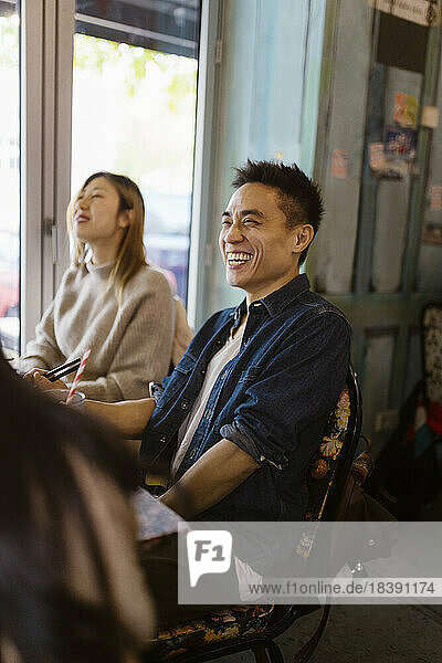 Mann lacht  während er mit einer Freundin im Restaurant sitzt