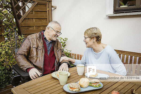 Älterer Mann und Frau im Ruhestand schauen sich beim Frühstück im Hinterhof an und unterhalten sich