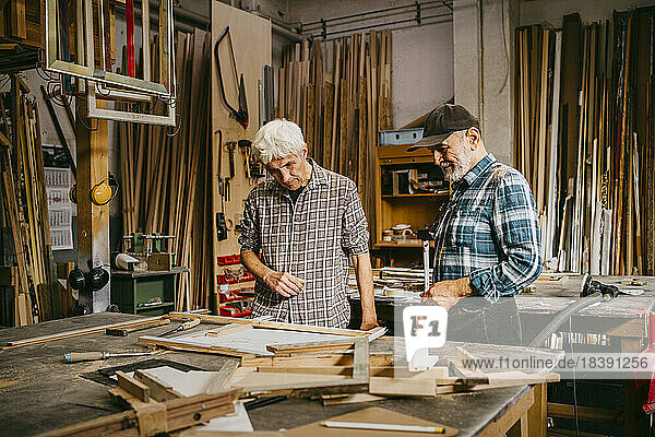 Senior craftsman discussing together while working at repair shop
