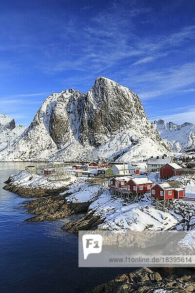 Rote Rorbuer im Winter  Fischerhütten  hinten schneebedeckter Berg Festhæltinden  Hamnøy  Lofoten  Nordland  Norwegen  Europa