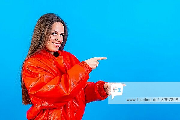 Attraktive Frau lächelnd zeigt mit den Fingern auf Kopie Raum auf blauem Hintergrund  rote Windjacke