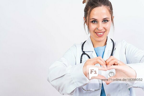 Portrait of smiling female doctor in medical gown standing isolated on white  medicine concept  heart gesture