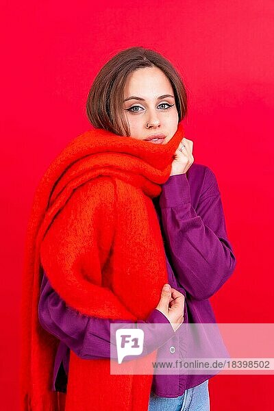 Schöne junge Frau mit warmen roten Schal auf rotem Hintergrund. kalten Winter Porträt
