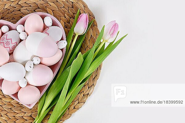 Ostereier in herzförmigem Teller und Tulpenblüten mit Kopierraum
