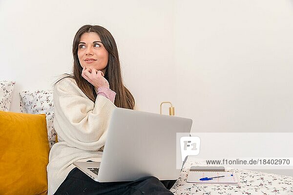 Porträt einer Frau mit Laptop im Bett  nachdenklich  Telearbeit