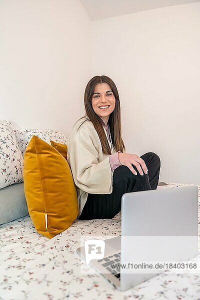 Porträt einer Frau  die mit einem Laptop auf dem Bett arbeitet  Telearbeit